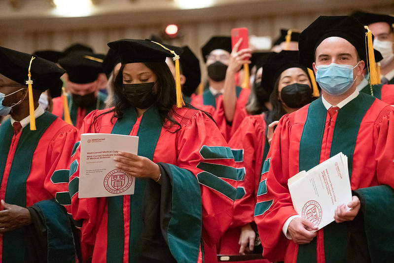 Masked students in regalia stand in Carnegie Hall