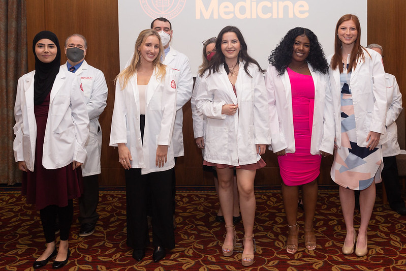 Six members of the Physician Assistants Class of 2023 smile as they receive their white coats.