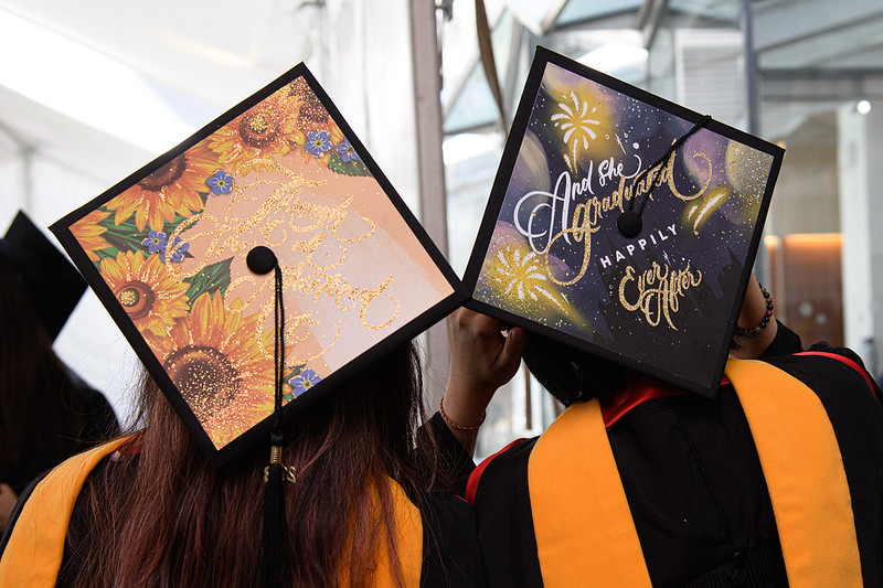 Graduating doctoral students wearing decorated graduate hats.