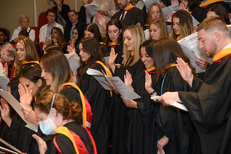 Graduating physician assistant students raise their right hands as they recite an oath.