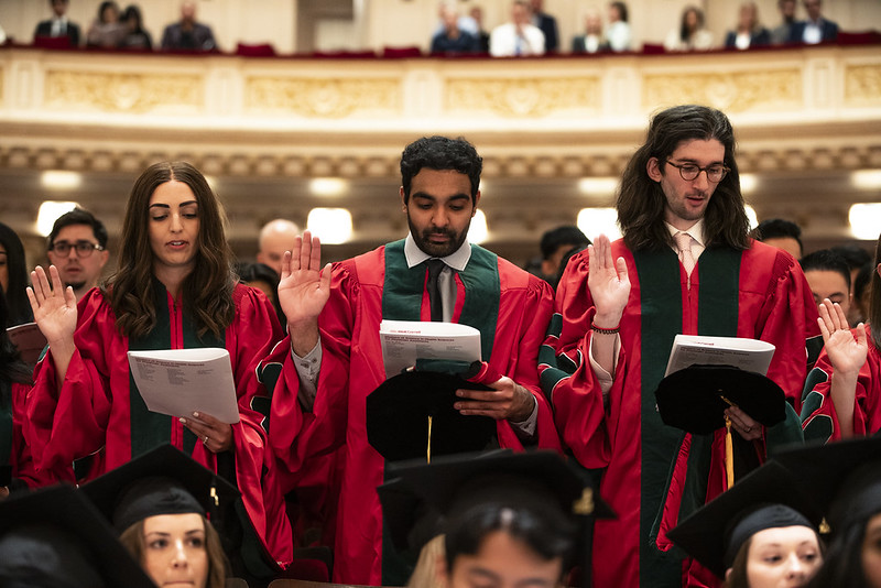 Graduates with their hands raised performing an oath