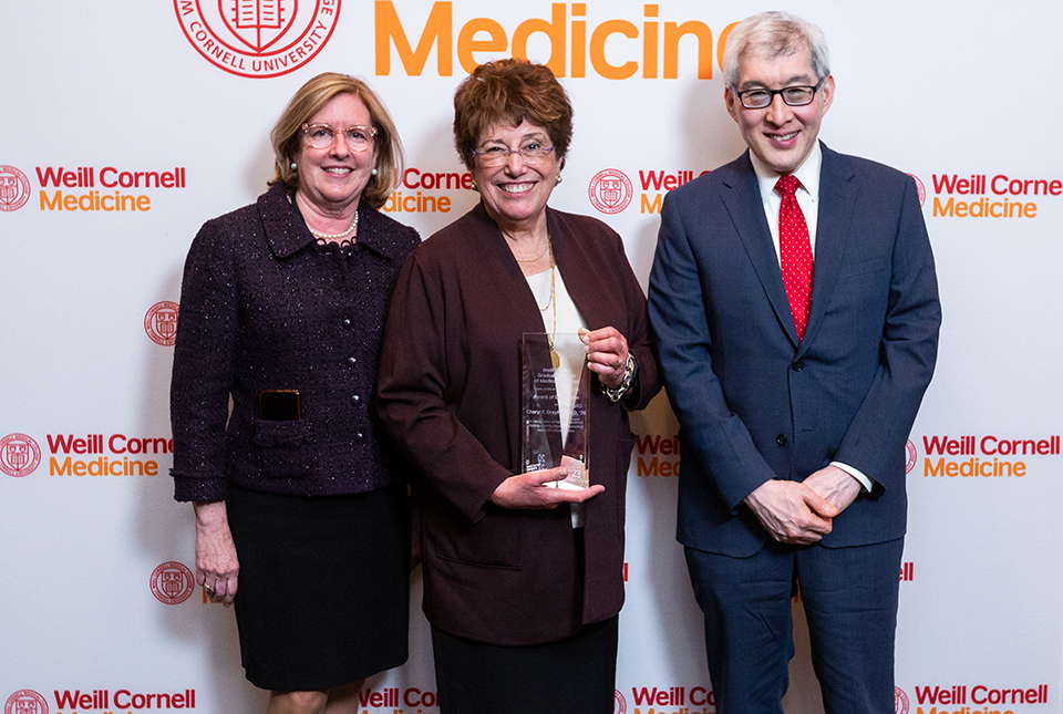 Drs. Barbara Hempstead, Cheryl Dreyfus, and Francis Lee posing in front of a Weill Cornell Medicine branded backdrop. 