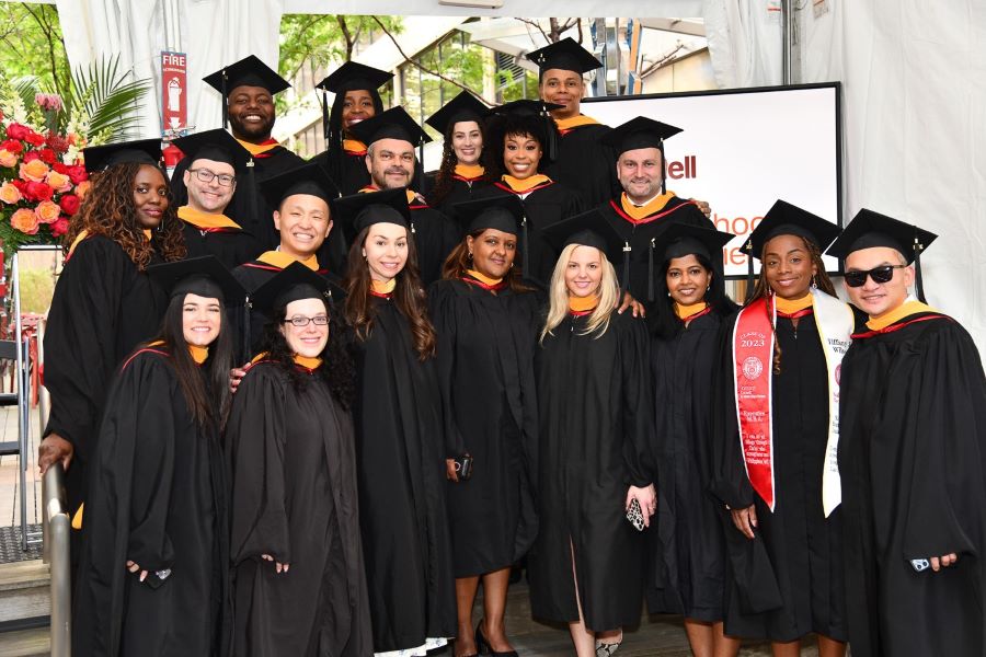 Graduating students wearing regalia pose for a group photo.