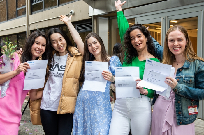 Five celebrating students show their match letters.