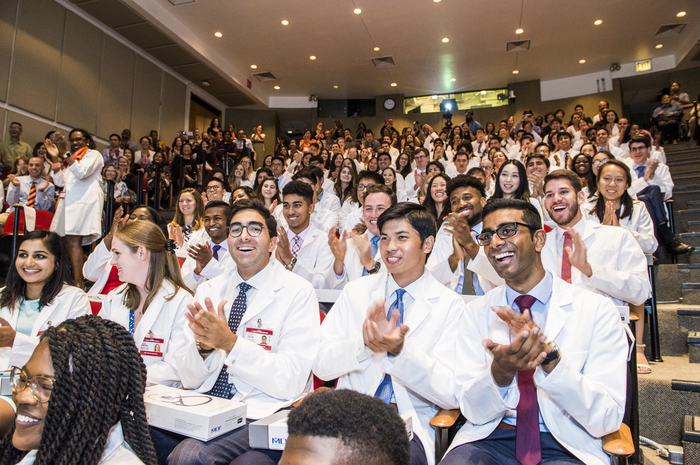 Students from the Class of 2023 celebrates receiving their white coats in Uris Auditorium.