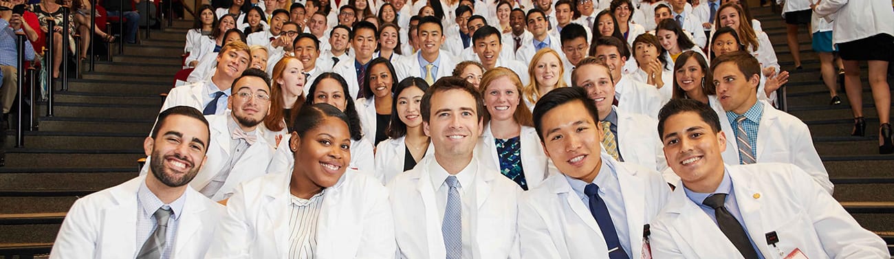 WCM students in white coats in the auditorium.