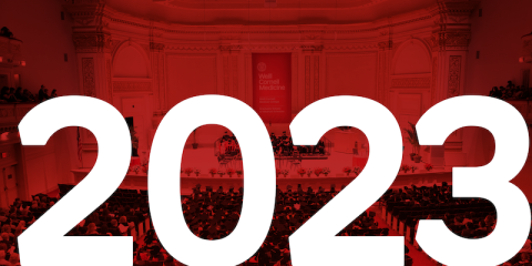 A decorative graphic showing a Carnegie Hall commencement ceremony with a red overlay. "2023" appears in white over top of the photo.