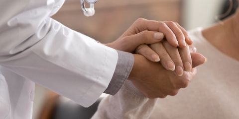 Two people, one in a white coat, clasping hands