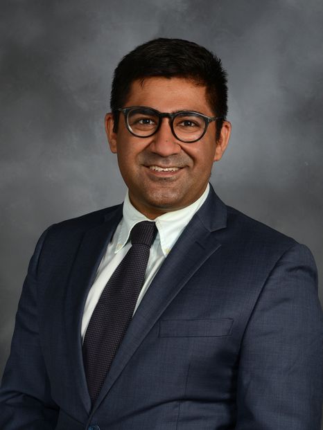 a man in a suit and glasses smiling for a portrait
